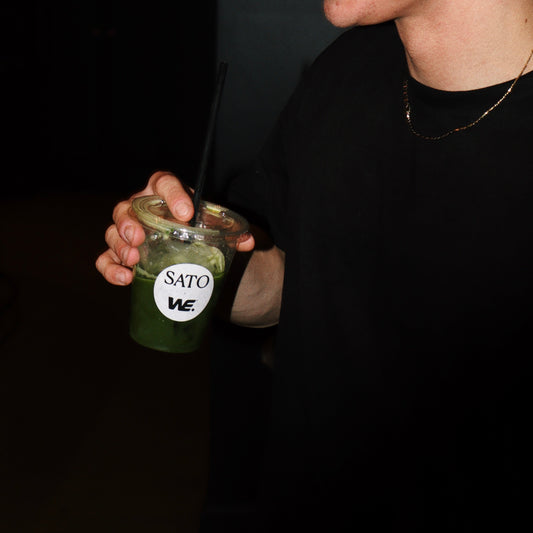 A hand holding an iced coconut water matcha with fresh mint after a boxing workout